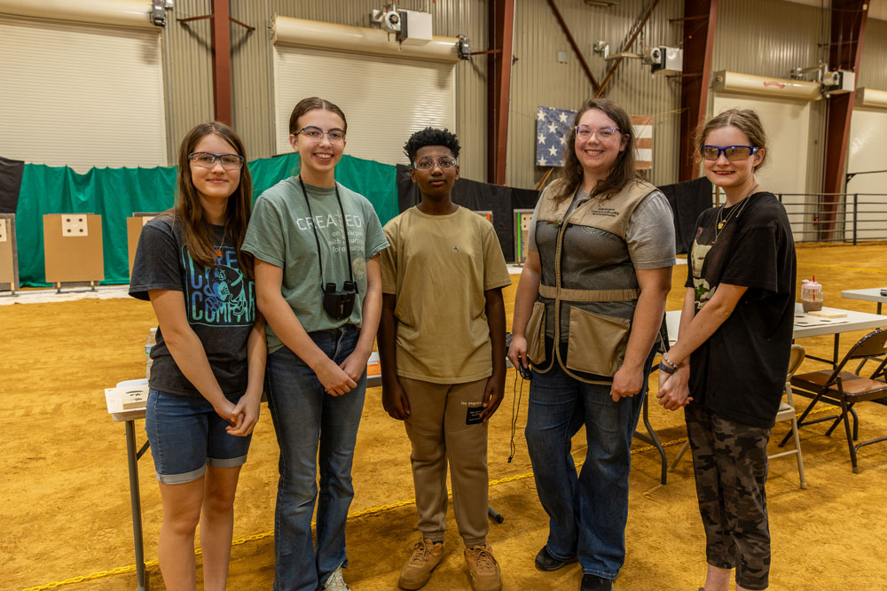 Four teens standing with an adult in a show ring.