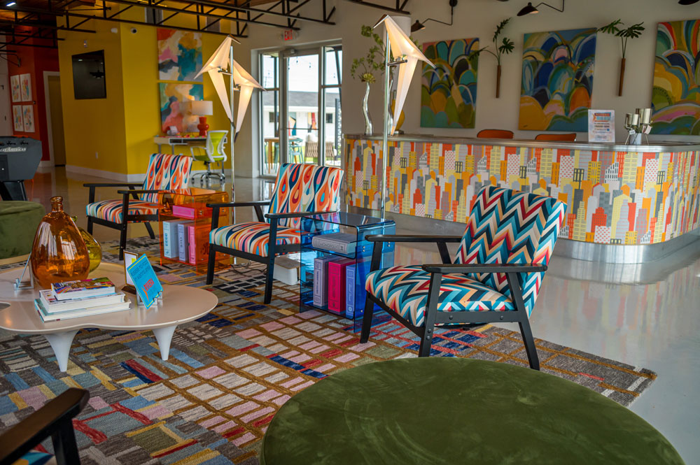 A hotel lobby seating area with brightly decorated furniture, walls, and rug.