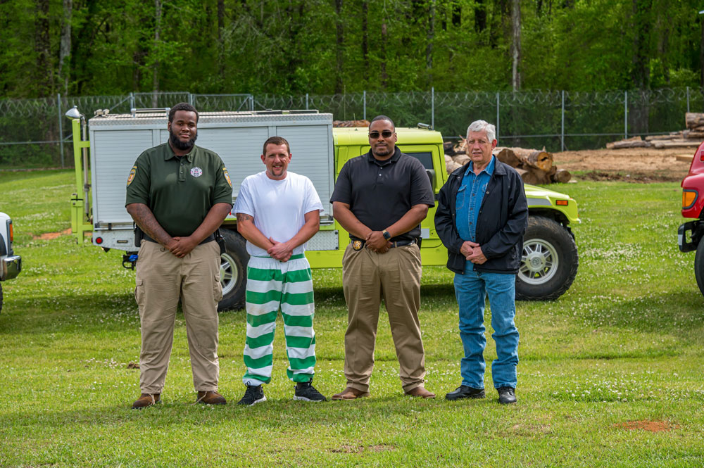 Four people standing outside in front of a fire truck.