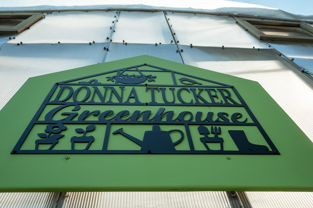 A greenhouse-shaped sign displaying the words Donna Tucker Greenhouse.