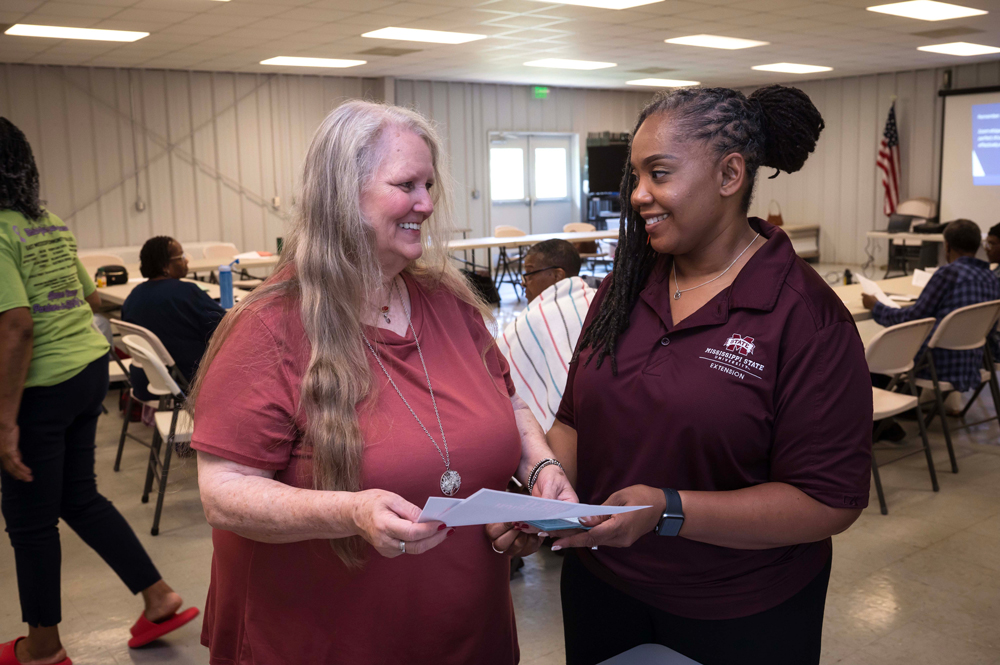 Two women smile at each other as they review a document.