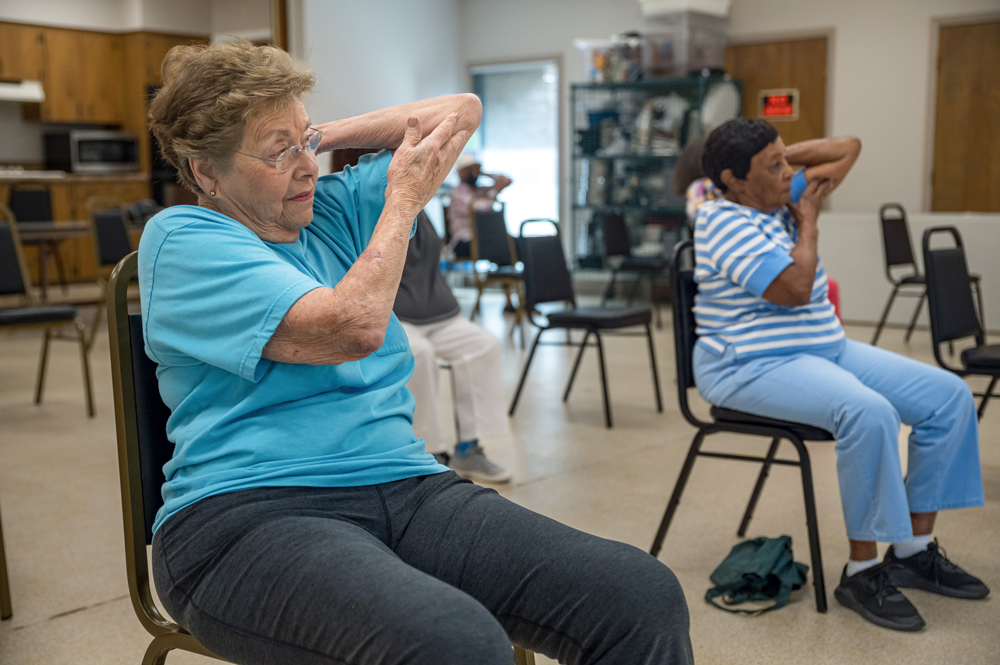 Two women doing chair exercises with their arms.