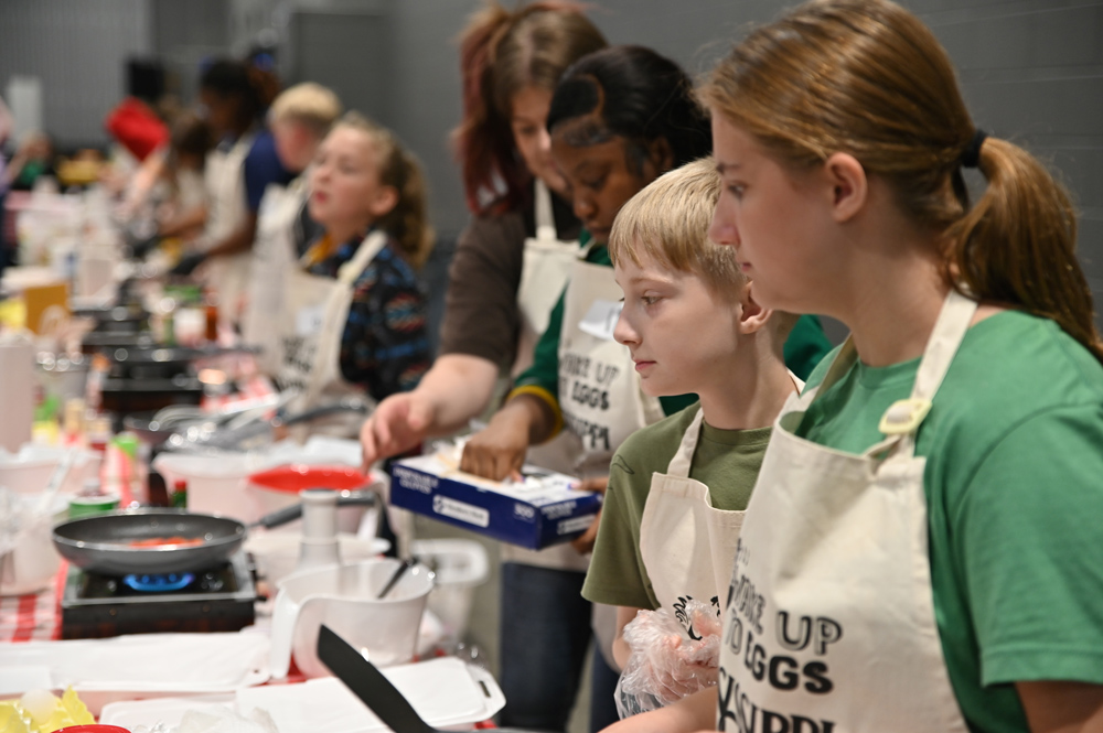 Children stand along a cooking line.