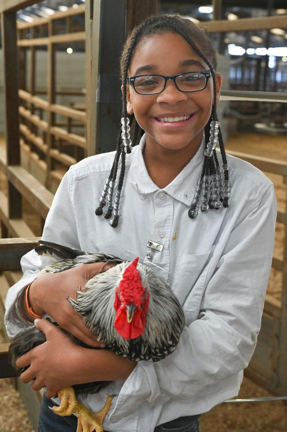 A girl is smiling while holding a chicken.