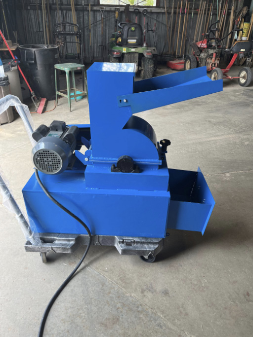 Small, rectangular crusher with a prominent tray-like opening positioned on a portable platform trolley on pavement.