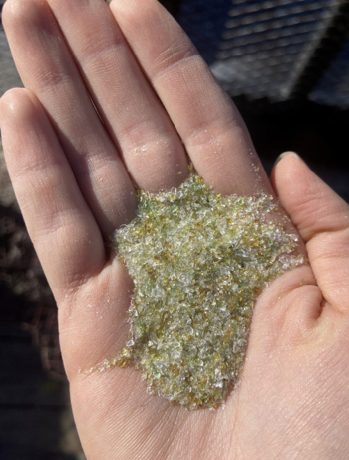 A hand holding a pile of glass sand.