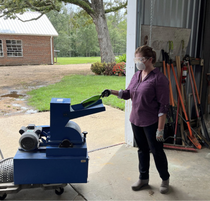 A person places a bottle into the inlet of a pulverizer.