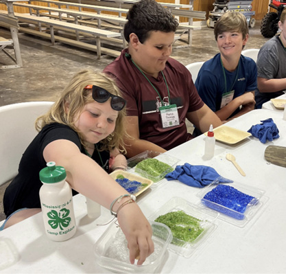 Children sit at a table while working on a glass sand recycling project.