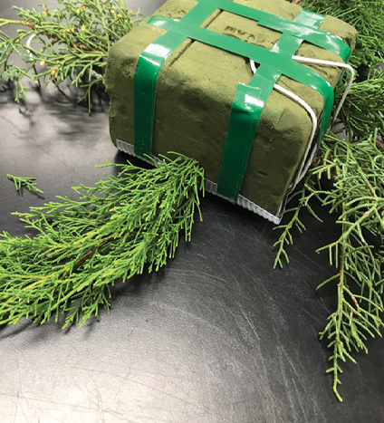 Prepared floral foam brick with a few pieces of greenery placed.