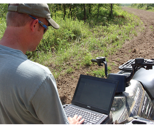 A person on an ATV uses a laptop. 