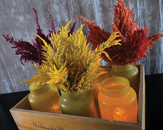 A bouquet of hot pink, dark red, and bright orange Celosia plumes and several bunches of greenery.