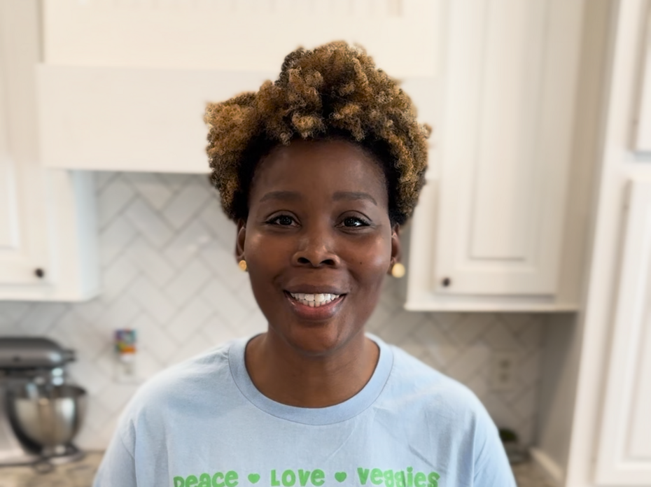 A woman stands in a kitchen with ingredients for a yogurt parfait on the counter.