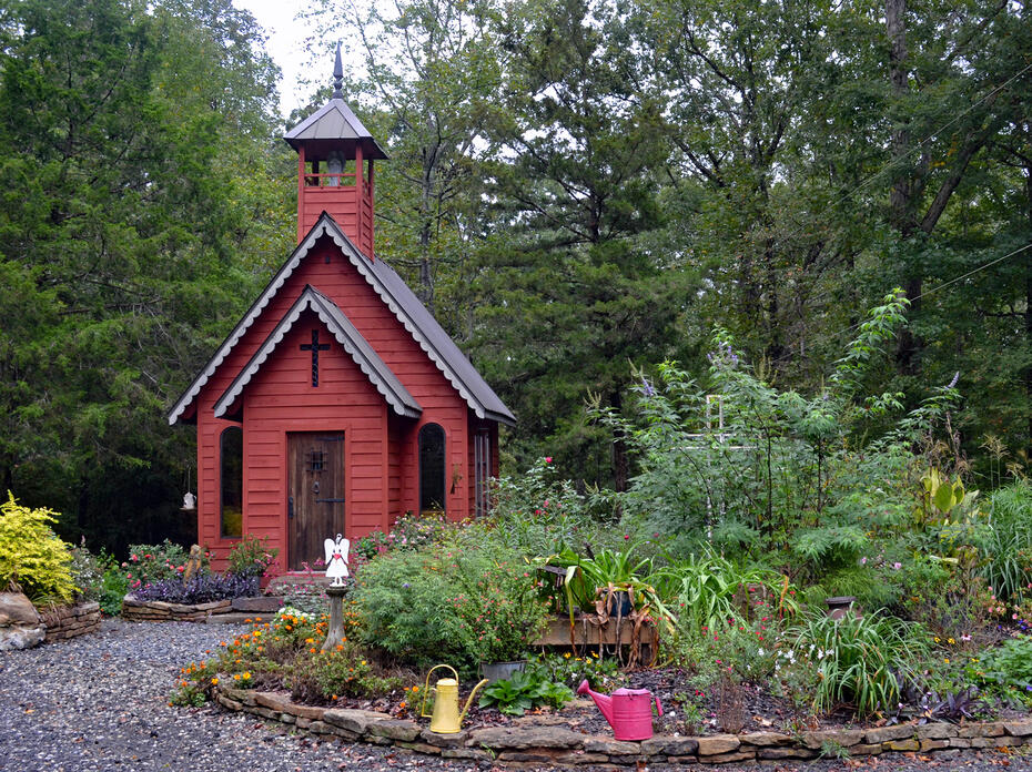 A small red structure stands in the center of a garden landscape.