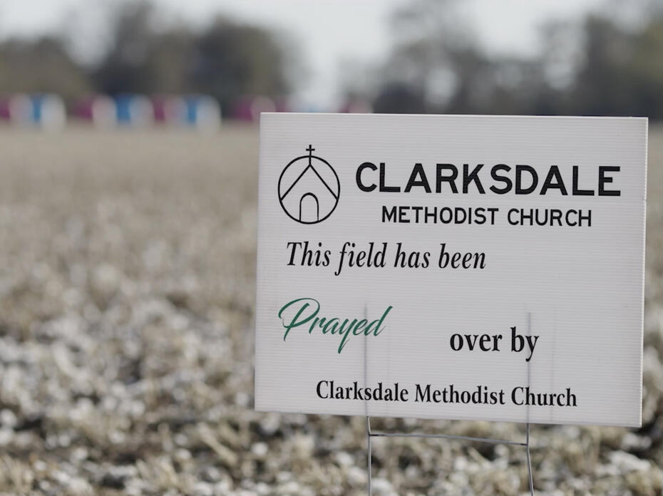 A small, white sign stands in field displaying the words, “This field has been prayed over by Clarksdale Methodist Church.”