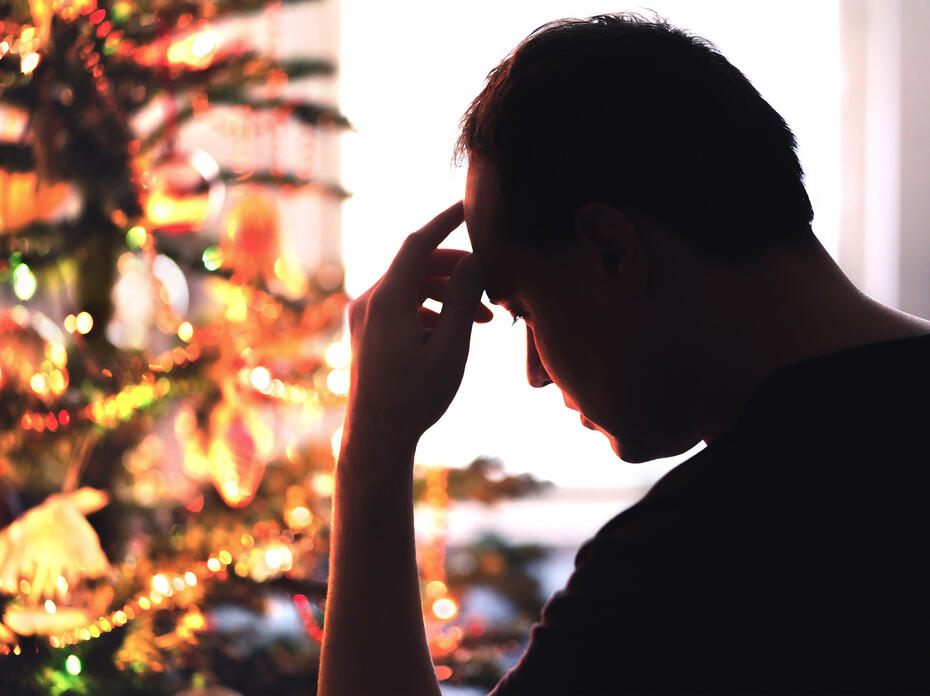 Man stressed out looking at a Christmas tree.