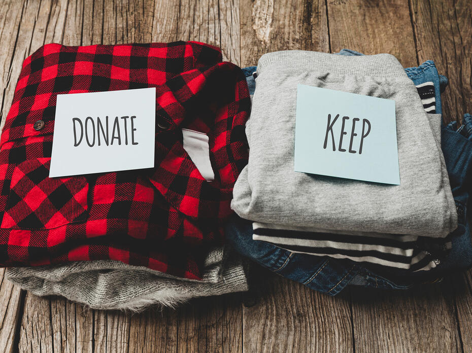 Two piles of clothes. One with donate on it, the other with keep.