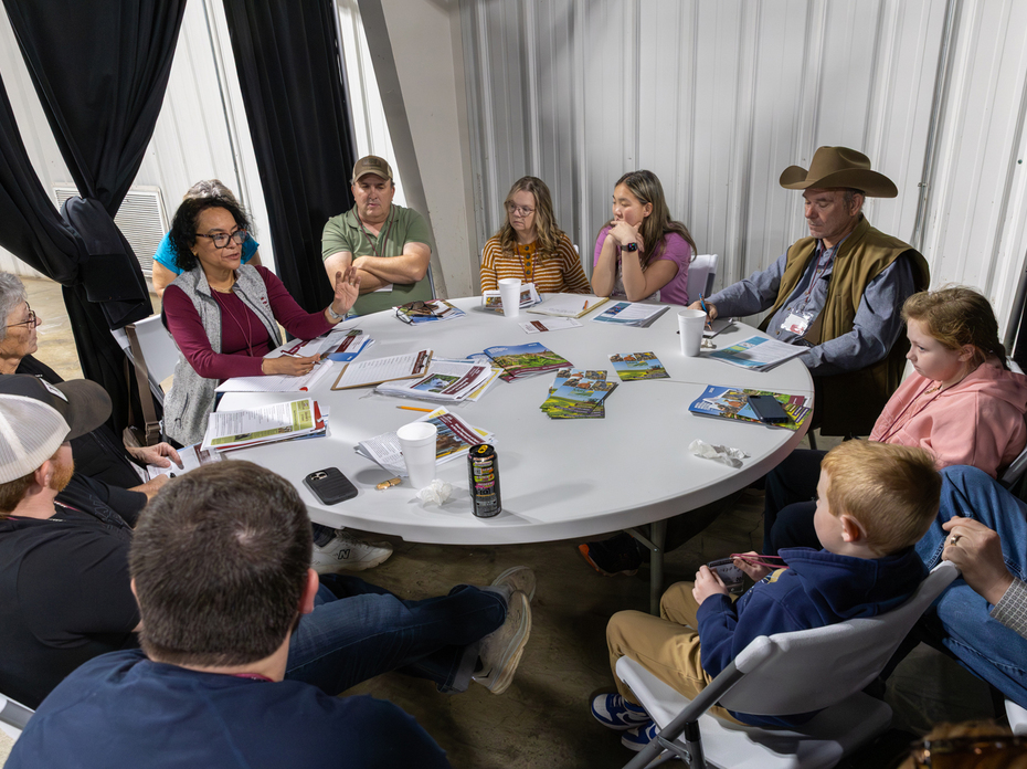 A circle of people sit in a meeting around a table.
