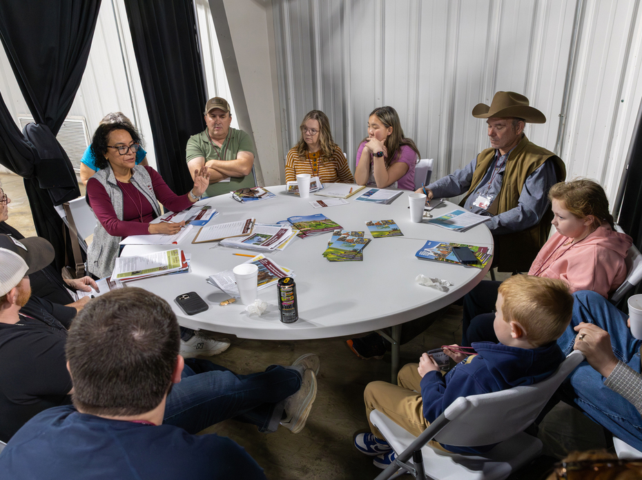A circle of people sit in a meeting around a table.