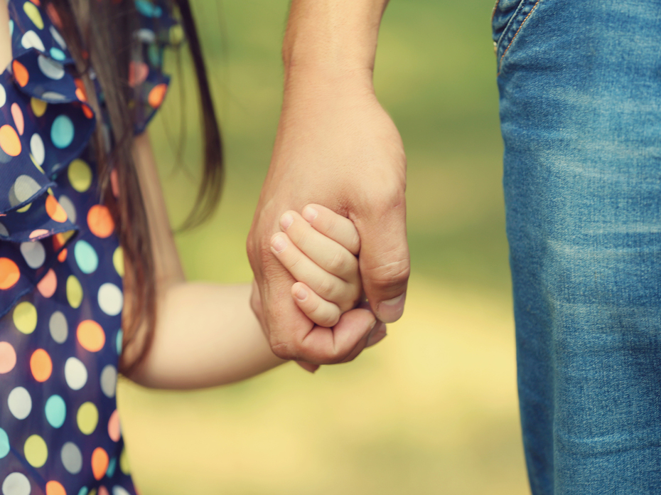 Close up picture of an adult holding a child's hand.
