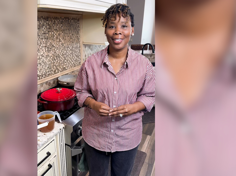 A person stands in a kitchen in front of the stove.
