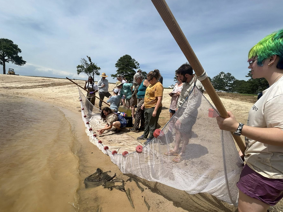 A group of people casting a new on the shore of the ocean.