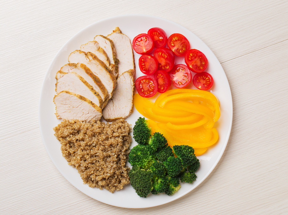 A plate with tomatoes, yellow peppers, broccoli, quinoa, and chicken.