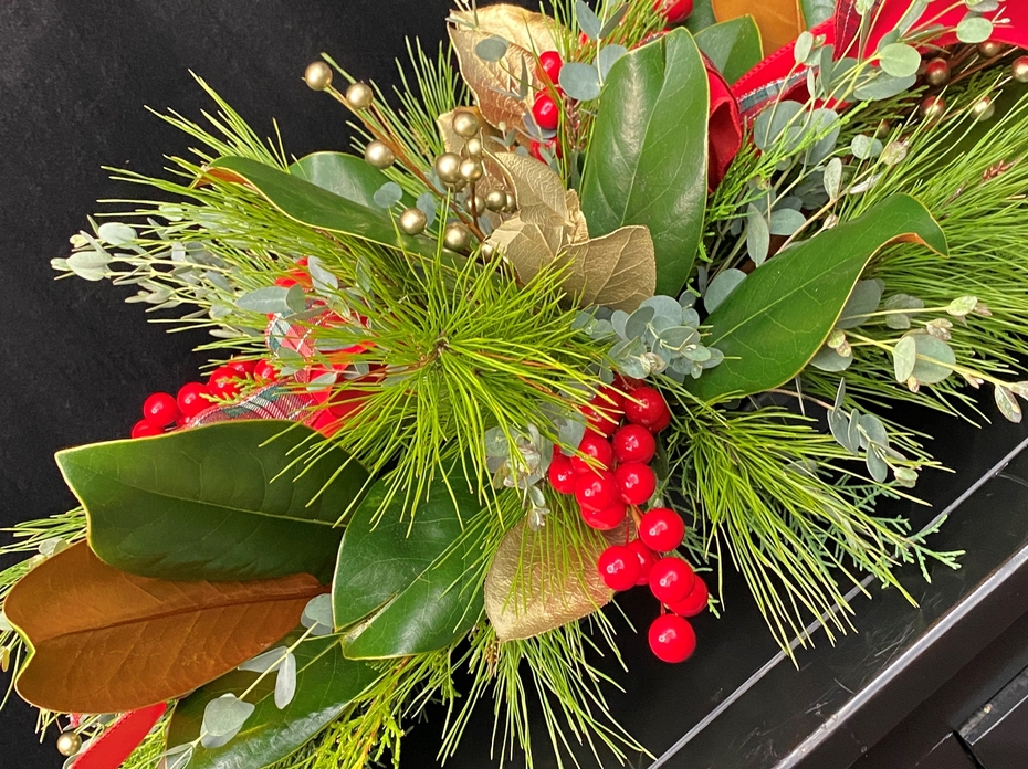 Table centerpiece of evergreens and red berries.