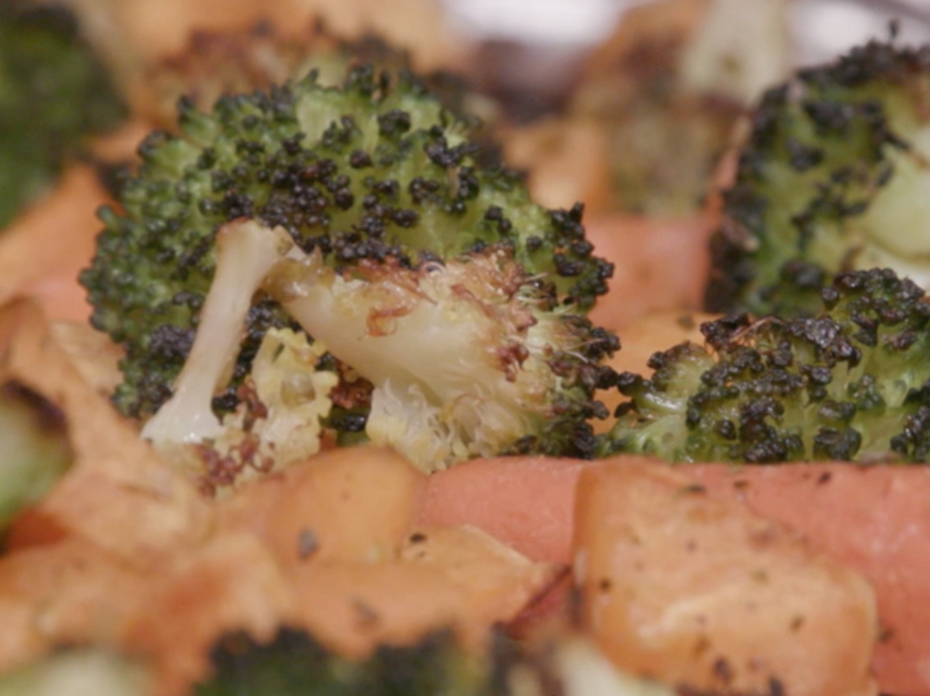 Roasted and seasoned broccoli florets, sweet potato chunks, and whole baby carrots on a foil covered sheet pan. 