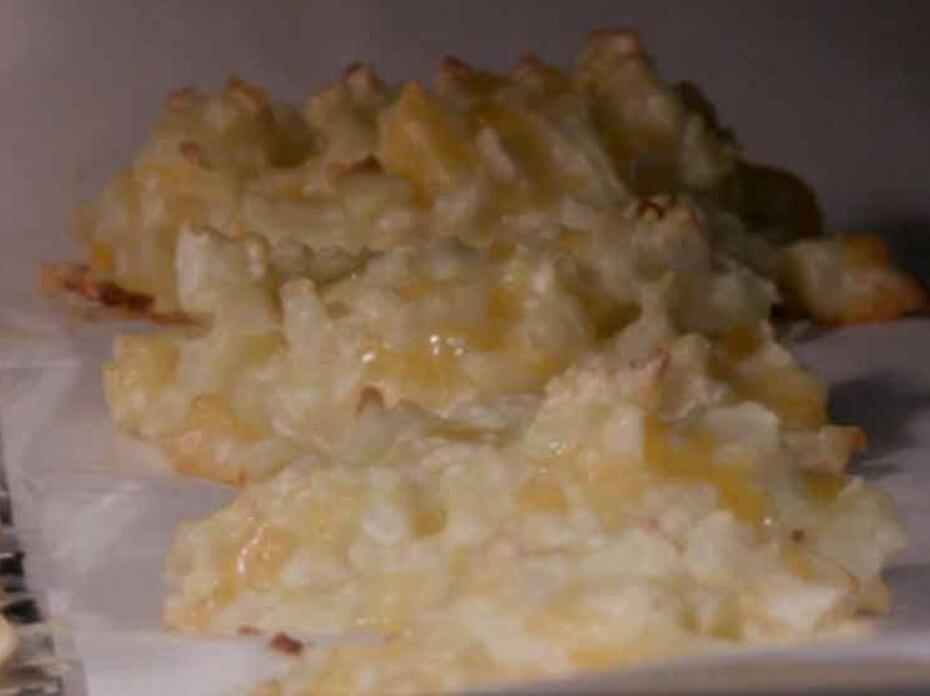 Cauliflower and cheese tots on a parchment-paper lined baking sheet.