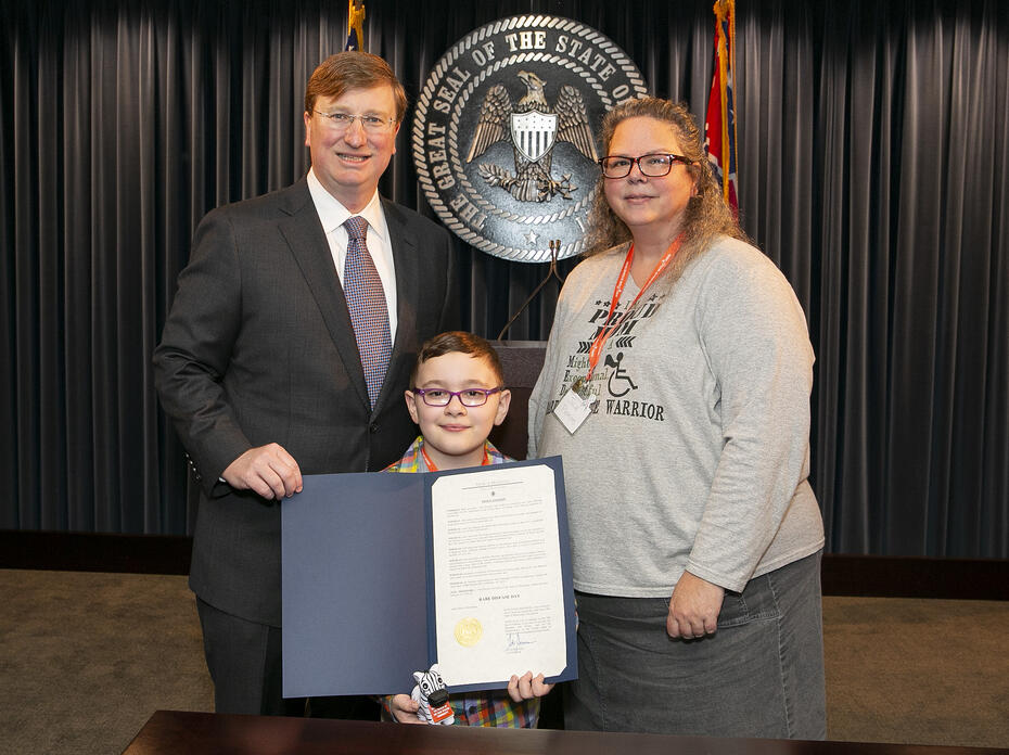 Three individuals pose with a newly signed proclamation.