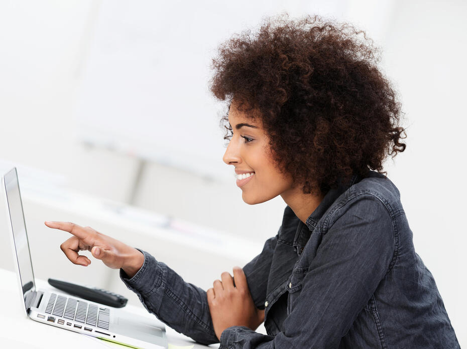 Woman points at computer screen.