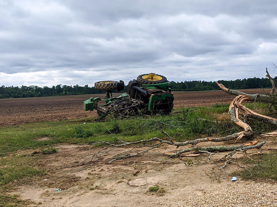Green tractor flipped on its side in a field.