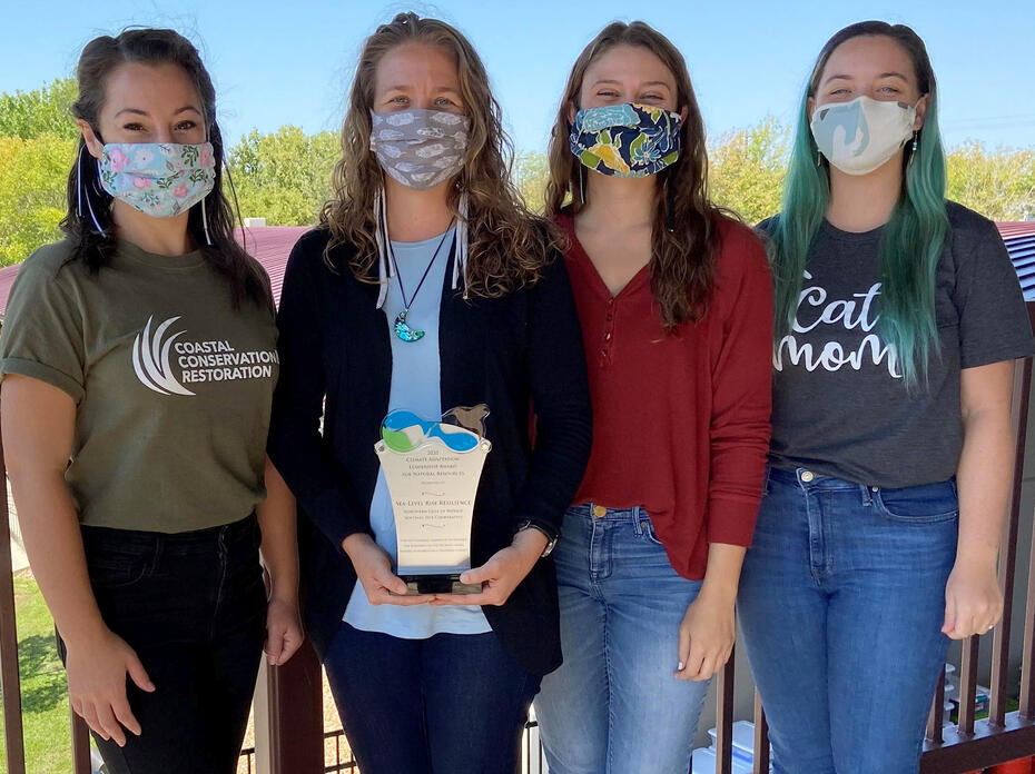 Four women pose with an award.