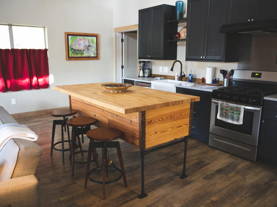 A serving island and three stools sit in a kitchen.