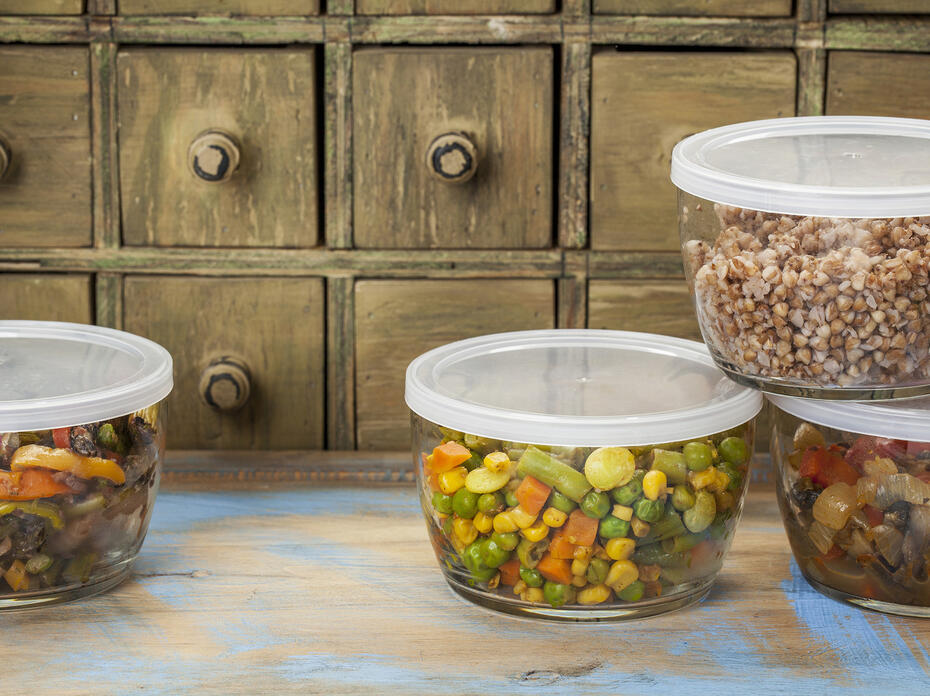 Four glass containers with plastic lids contain food leftovers.