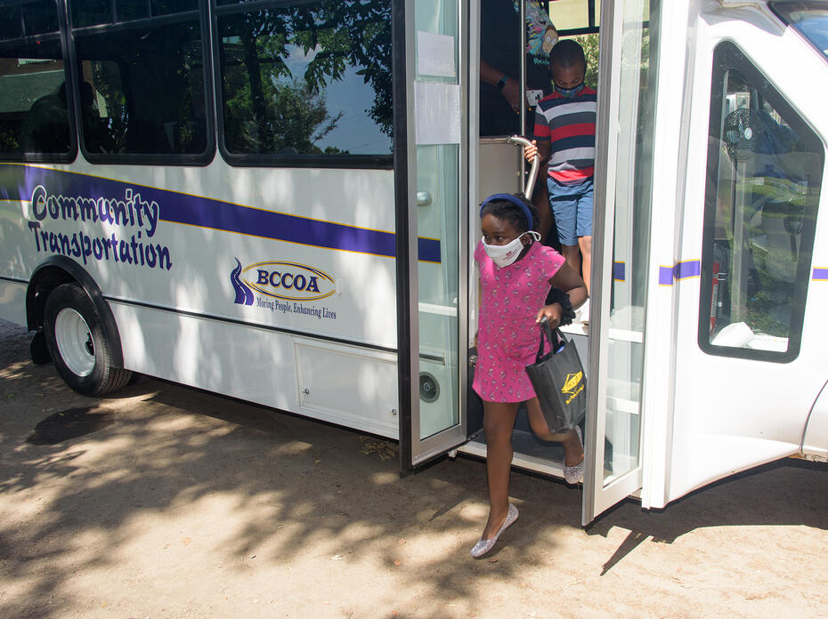 Two people step off a bus.