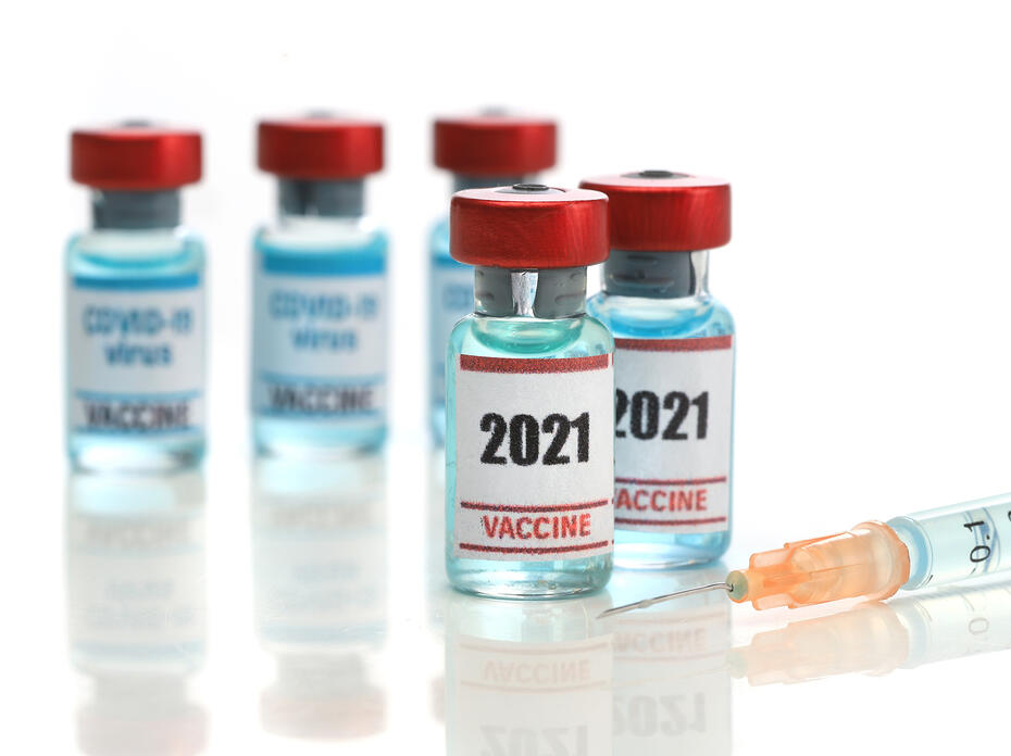 Two medical ampoules of COVID-19 vaccine with a syringe.