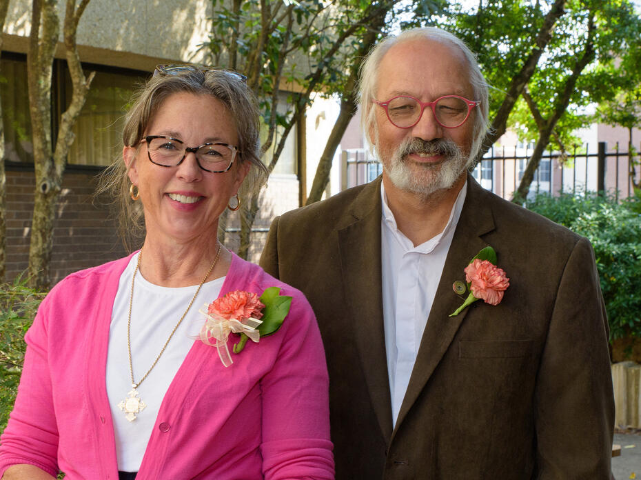 A man and a woman pose in a garden.
