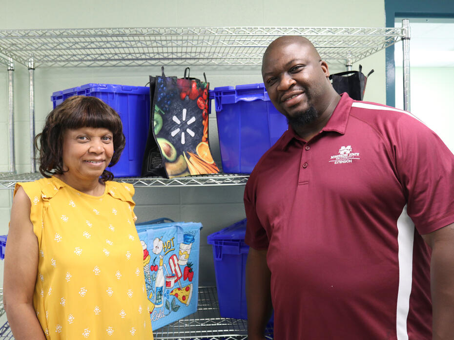 A woman and a man pose in front of shopping bags and blue crates.