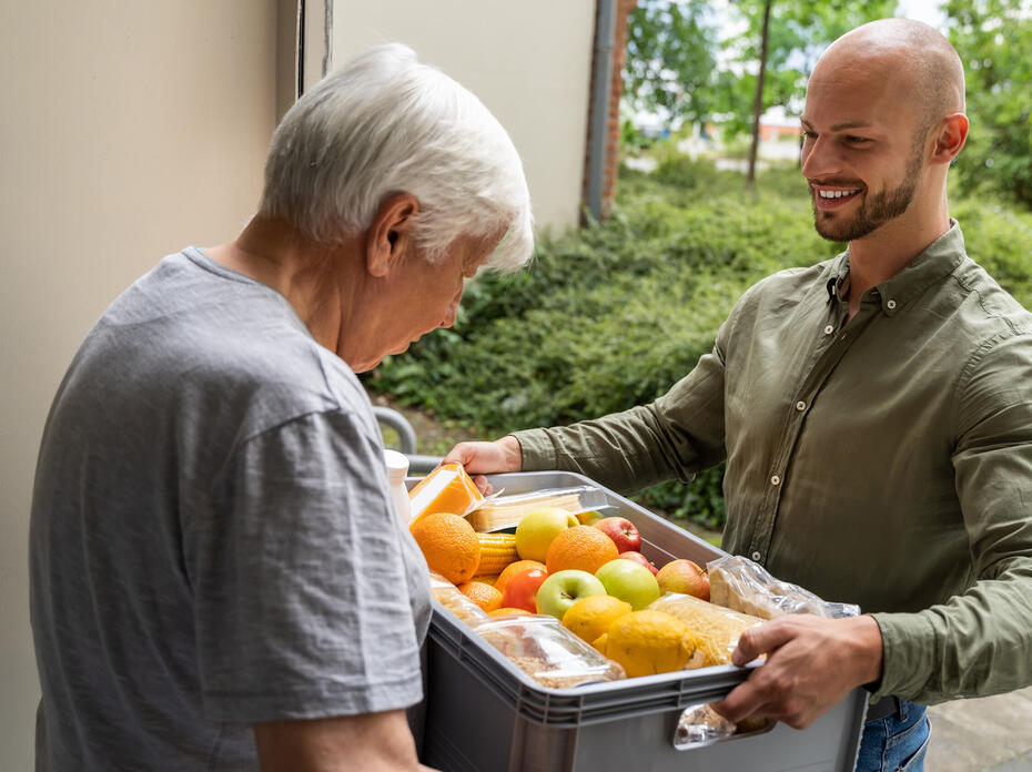 A man delivers a food box to a senior citizen.