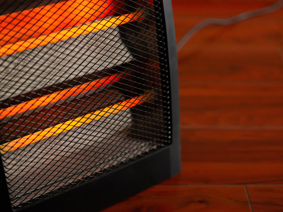 Close up of an electric space heater sitting on a hardwood floor.