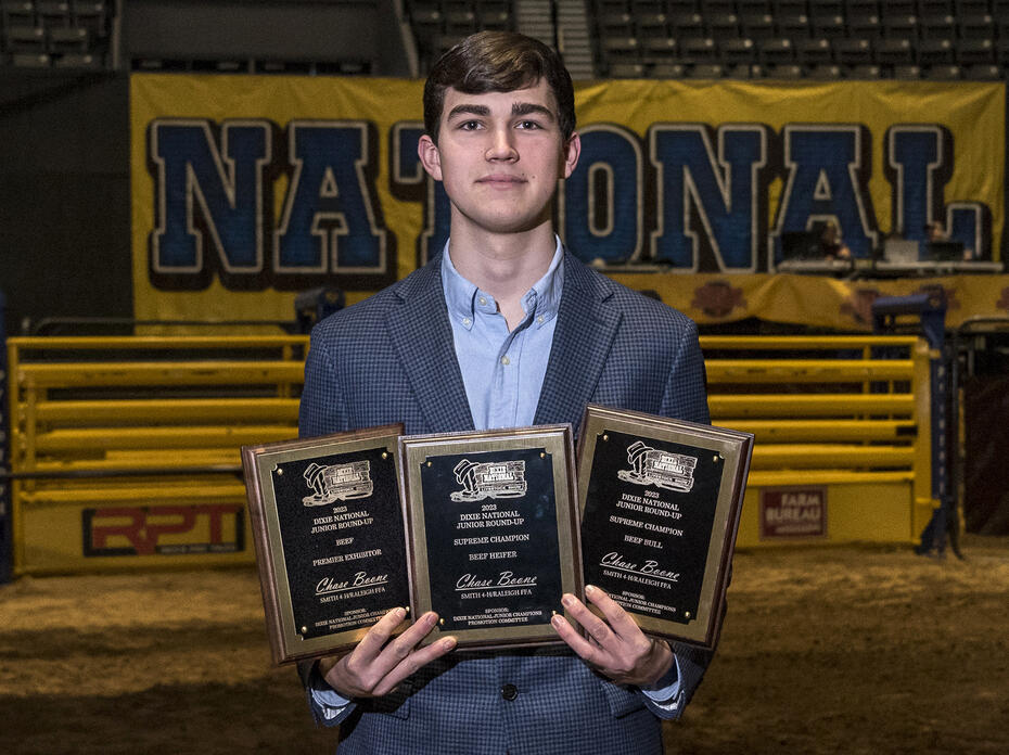 A young man holds three plaques.	