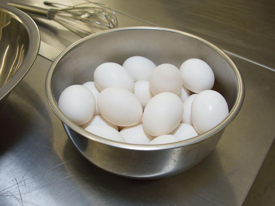 White eggs fill a metal bowl on a countertop.