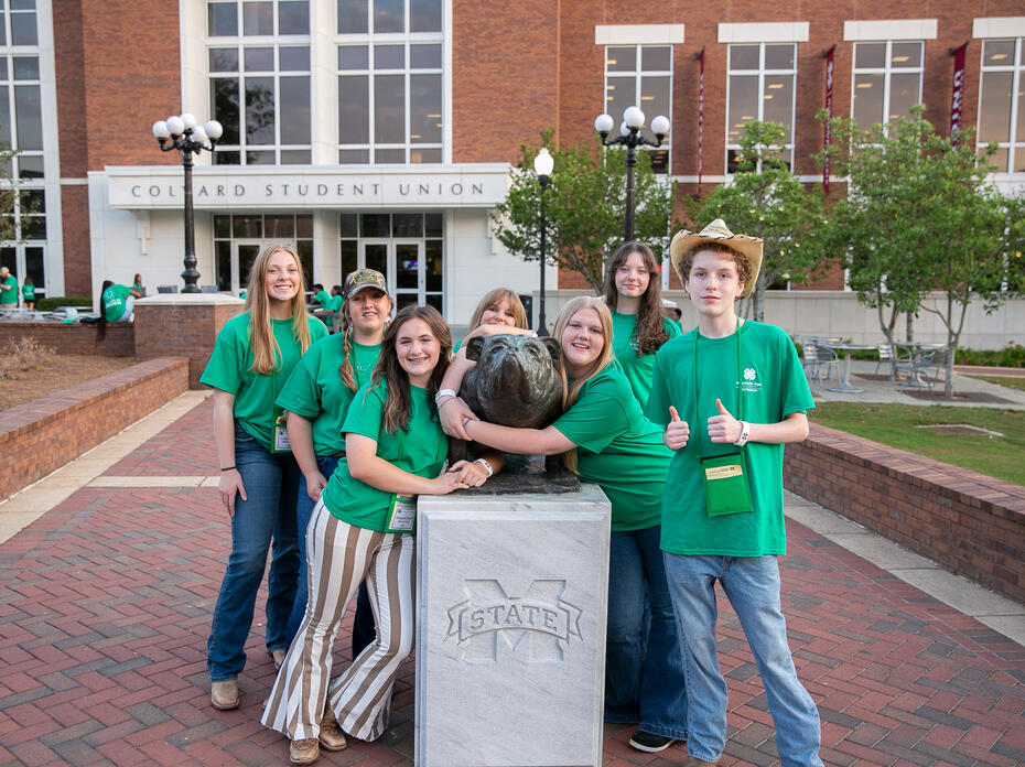 Students in green shirts posing for a picture. 