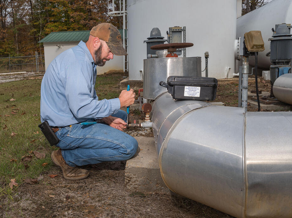 A man adjusts a valve on a water pipe.