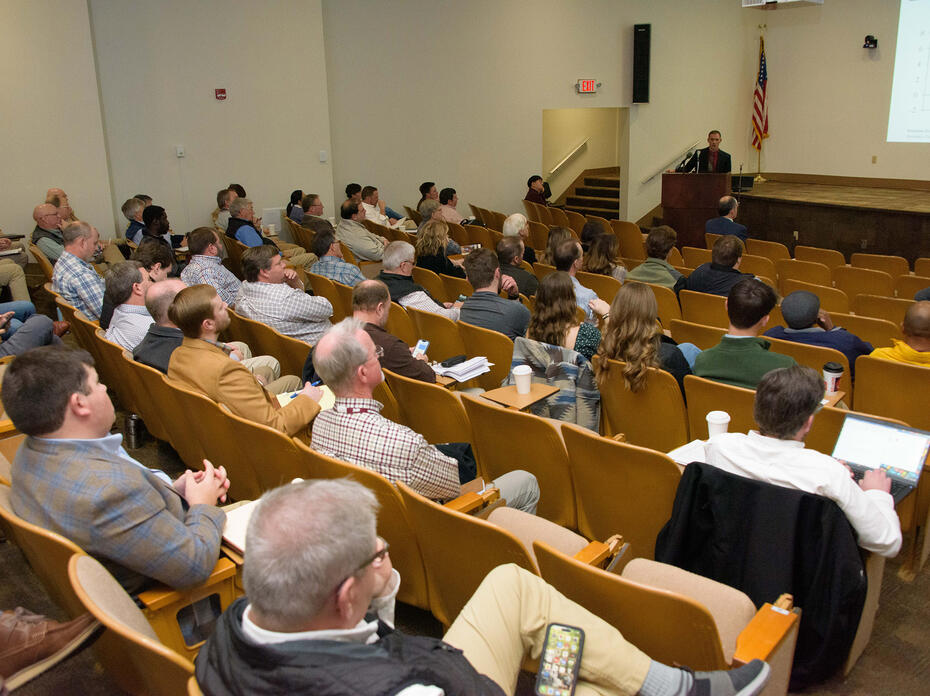 People in an auditorium watching a person give a presentation.
