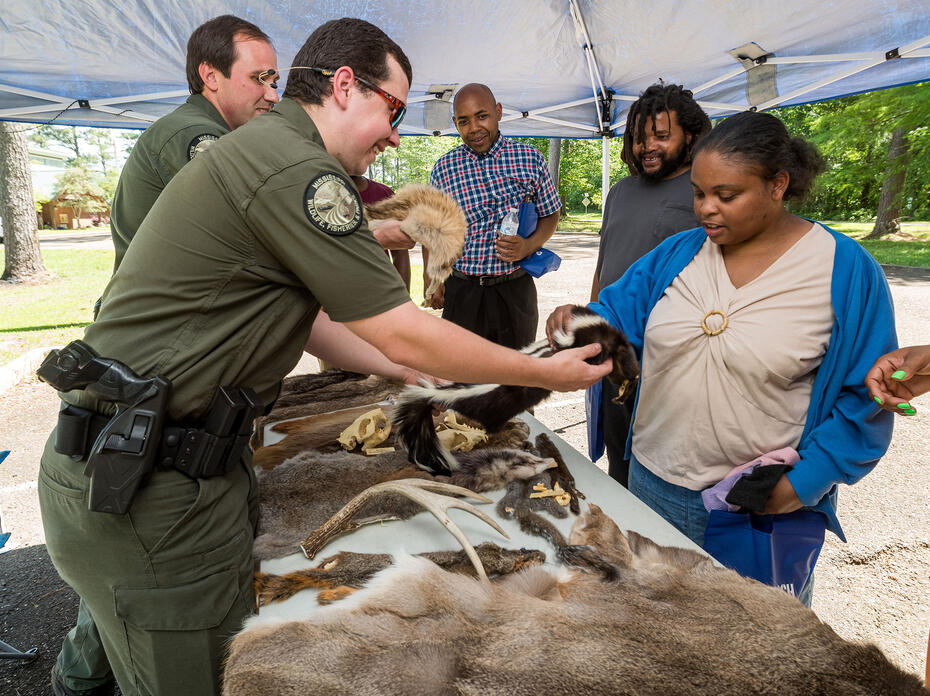 A man holds out a fur skin for a woman to touch.