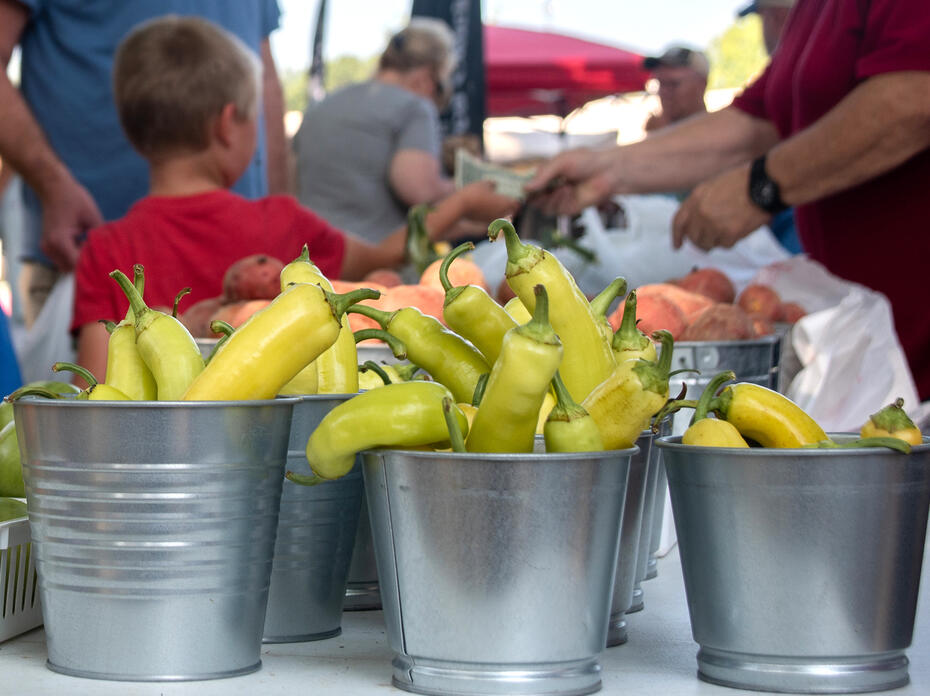 Buckets of peppers stand on a table at a market.