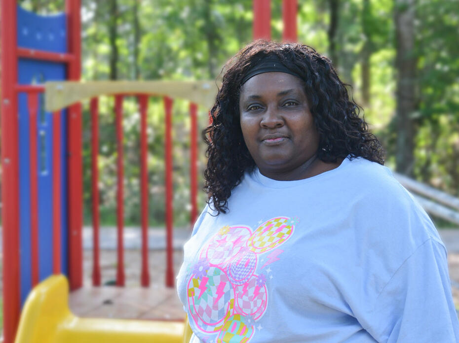 A woman stands outside in front of a playset.