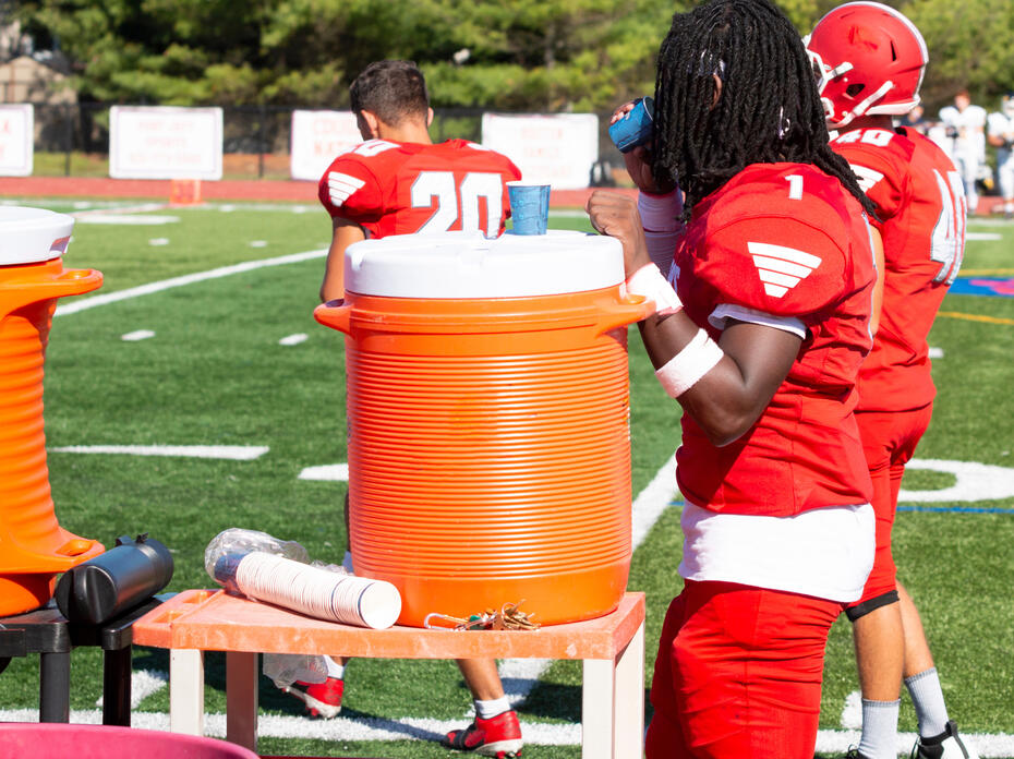 Football player getting water from a cooler.